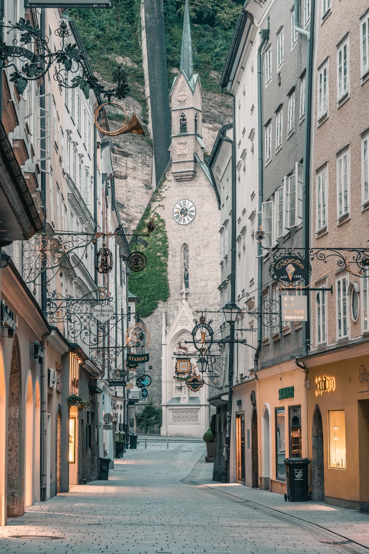 A quiet lane of guild signs in the old town, the church clock ahead