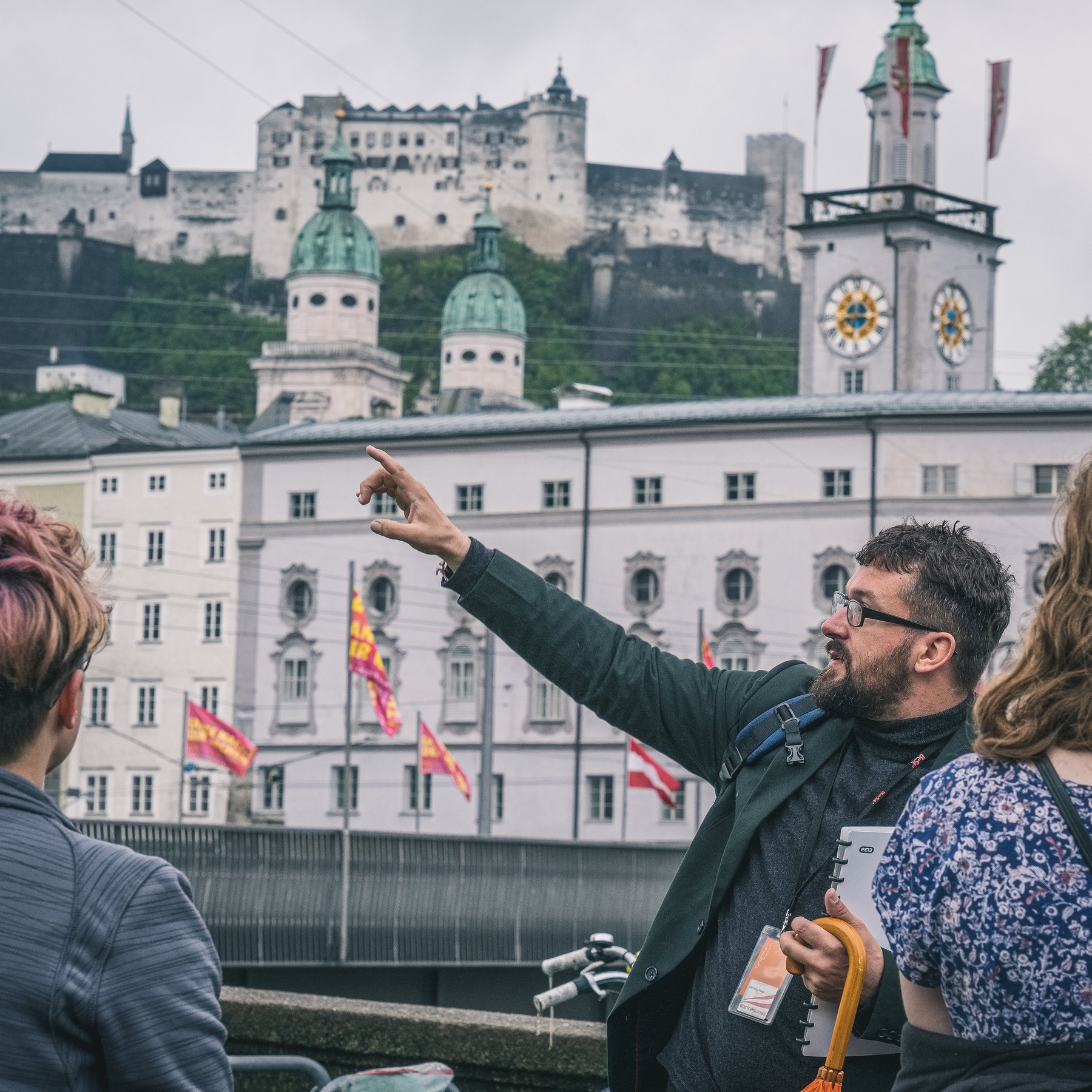 A guide pointing out the fortress to two guests above the old town